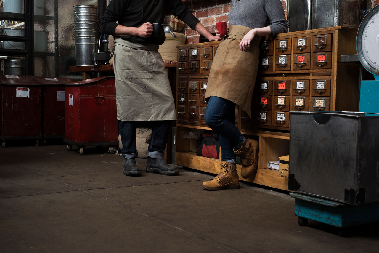 Small business owner standing in front a coffee machine at his cafe
